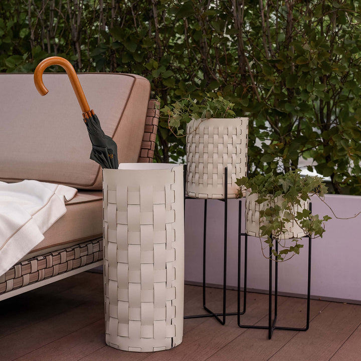 Decorative outdoor scene featuring a woven leather umbrella and various plants.