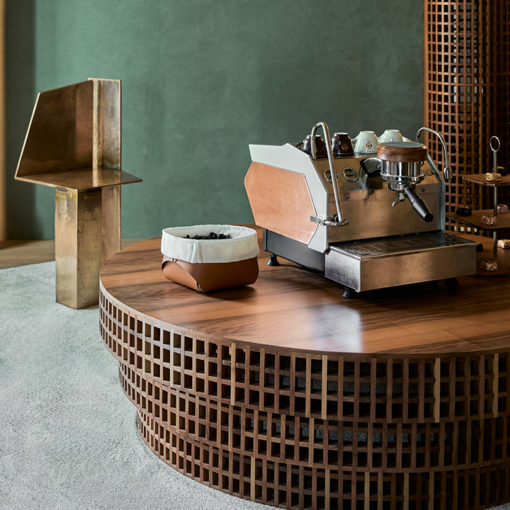 Modern coffee machine on a wooden table with a green wall in the background