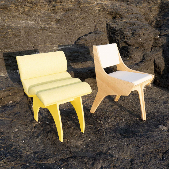 Calder Yellow chair by Jules Regis, bright yellow structure with soft cushions, contemporary designer seating on a rock