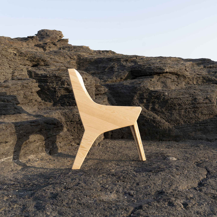 Falcone Cream chair by Jules Regis, oak wood structure with cream fabric upholstery, contemporary designer seating on a rock